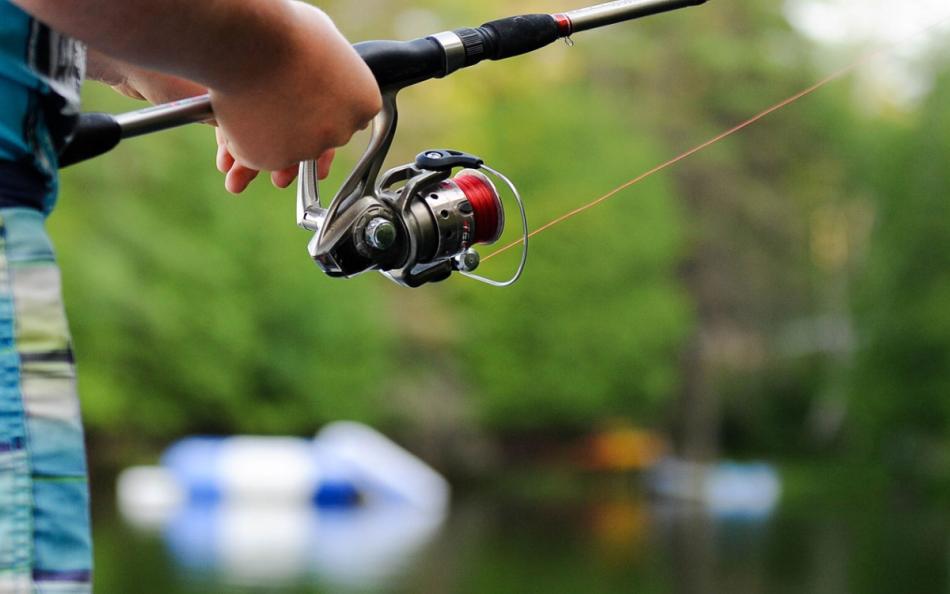 A Person Holding a Fishing Rod and Reel at the Lakeside