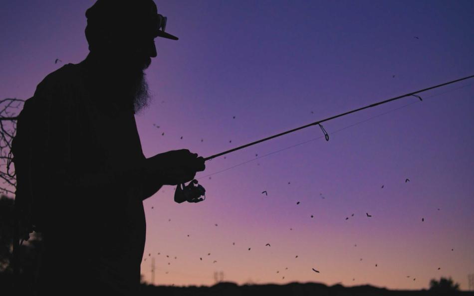 A Man Fishing at Dusk with a Beautiful Purple and Pink Sky