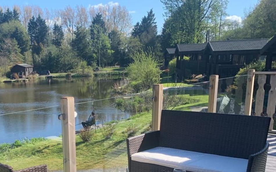 A View of a Person Fishing at a Lakeside taken from a Holiday Home Decking Area