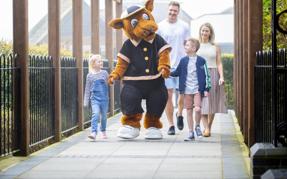 A Family Walking Along a Path with a Mascot for the Holiday Park