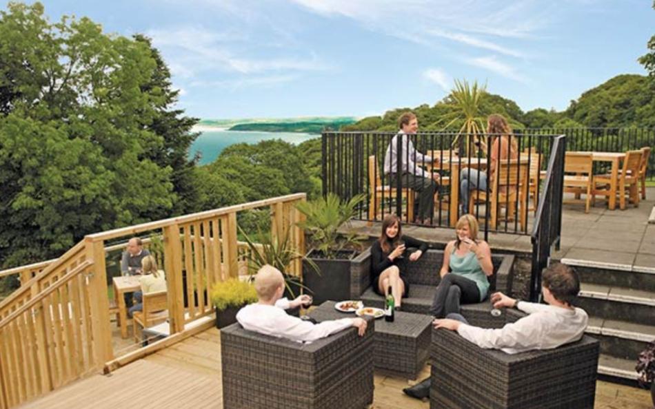An Image of People Enjoying Refreshments on a Terrace Overlooking the Woods and Sea