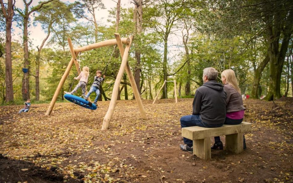 A Family playing on a Adventure Play Ground in the Woodland on a Holiday Park in Cornwall
