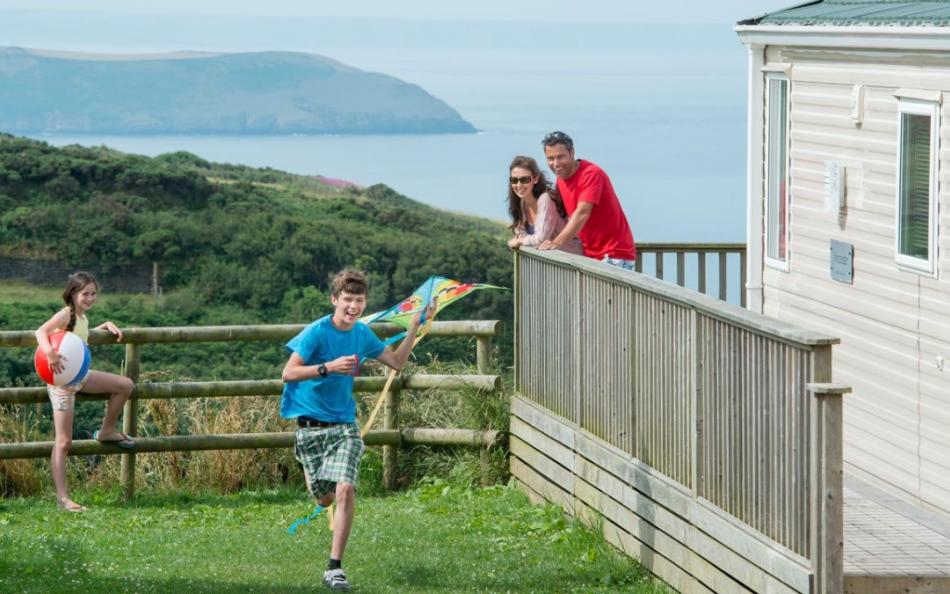 A Family Watching a Older Child Running with a Kite near to their Holiday Home with Far Reaching Sea Views in the Distance