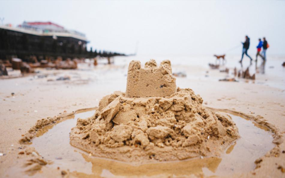 A Sandcastle on a Devon Beach with People Walking Past in the Distance