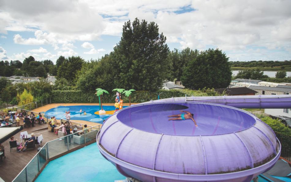 A Person Riding a Flume Ride on a Holiday Park in Blackpool with Other People Around the Pool