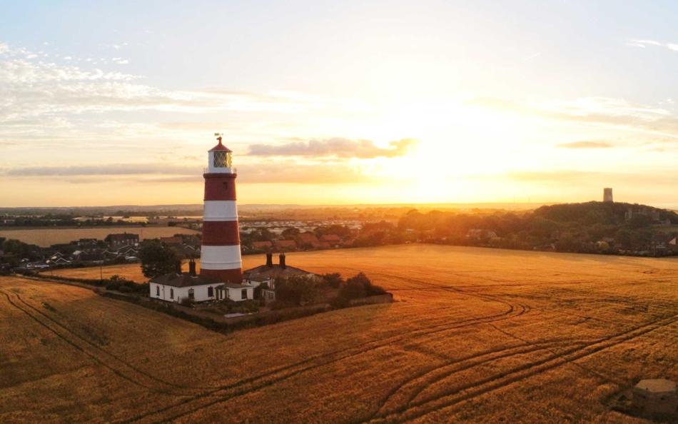 An Image of a Light House in a Norfolk Field at Sunrise