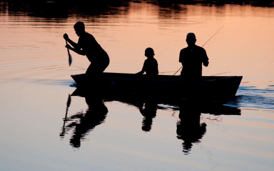 Three People in a Boat Silhouetted on a Lake 