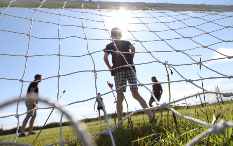 A Group of People Playing Football Behind a Goal Net