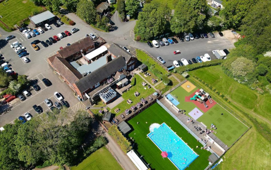 A View of a Swimming Pool, Childrens Play Area, Club House, Golf Green and Car Park from Above  