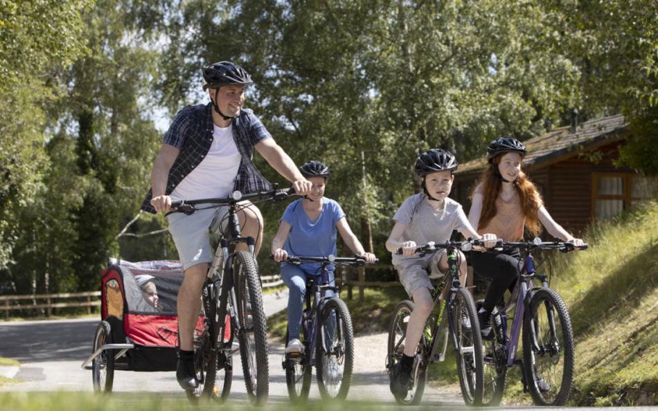 A Family Riding Bikes Along a Lane Through Forests and Woodland on a Weymouth Holiday Park