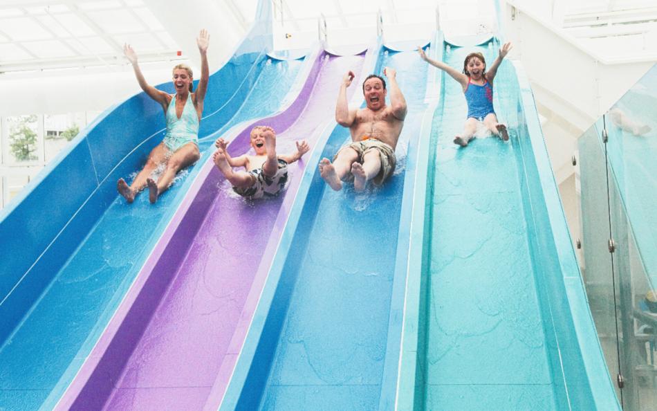 Four People Sliding down a Multi Coloured Four Laned Water Slide