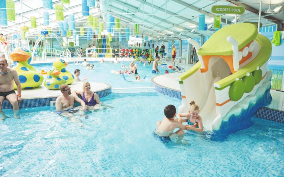 Lots of People Enjoying a Brightly Coloured Indoor Swimming Pool