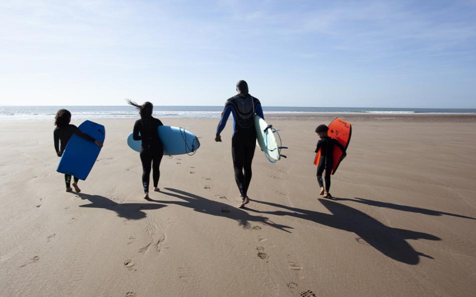 Four People Walking on a North Devon Beach with Surfboards and Bodyboards
