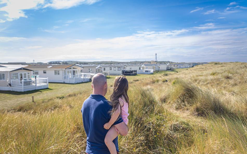 Two People Looking Towards Caravan Holiday Homes from The Nearby Sand Dunes