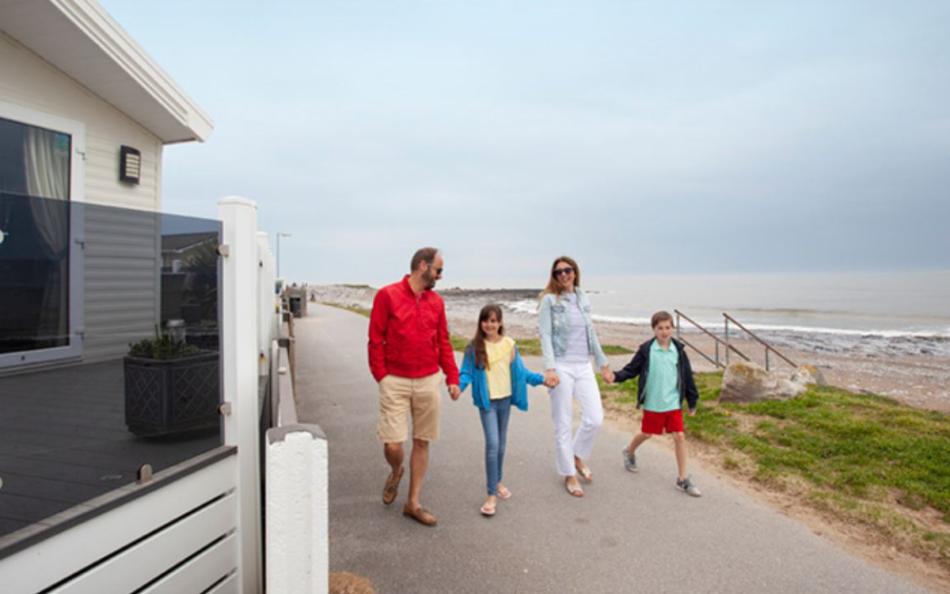 A Family Walking Along the Beach Front next to a Holiday Park