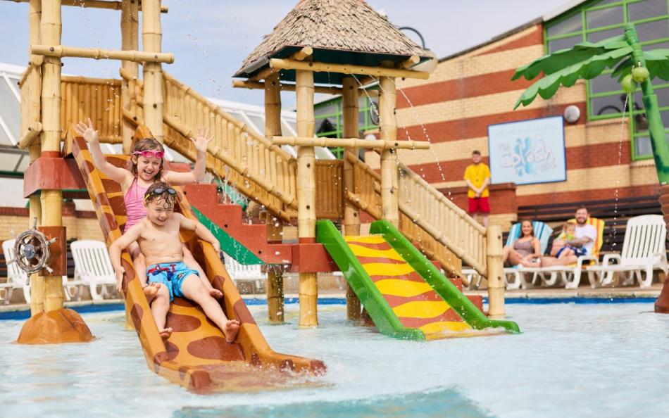 Two Children on a Water Slide in a Outdoor Swimming Pool Area