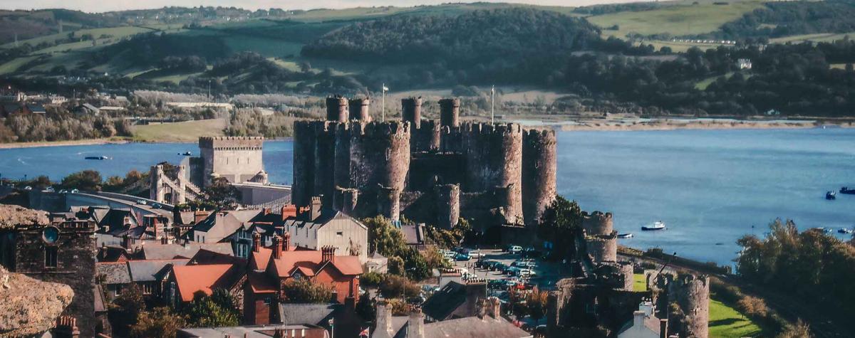 A view of Conwy castle and town with the sea and mountains in the background
