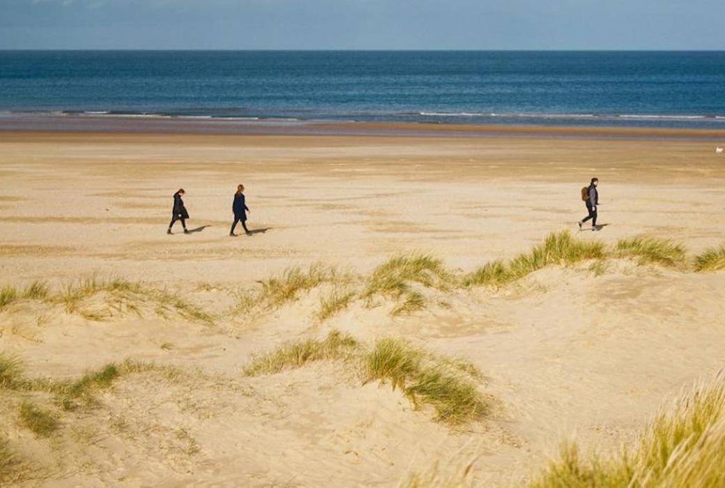 People Walking along a Golden Sandy Beach