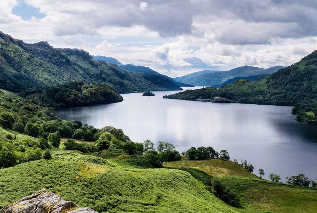 Scottish Loch surrounded by Green Rolling Hills & Forests