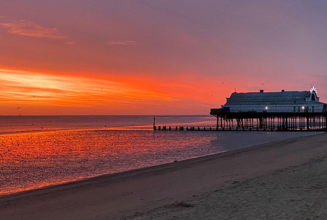 Pier with a Deep Red Sunset and Empty Beach