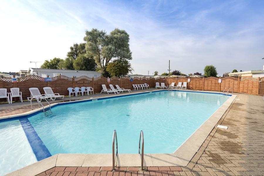 outdoor pool with sun loungers at Winchelsea Sands Holiday Park