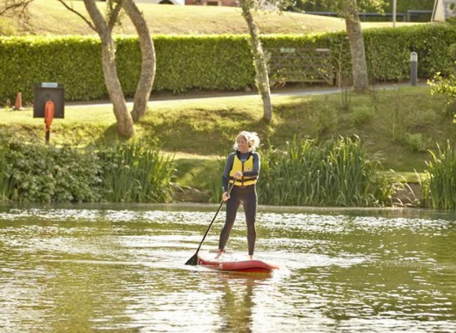 having fun on a paddleboard at The Lakes Rookley Holiday Park